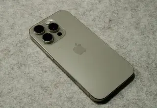 A silver iPhone sitting on top of a table in titanium finish