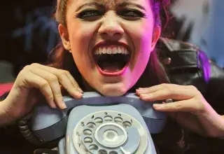girl holding gray rotary-dial telephone