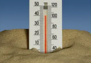 A thermometer in the sand with a blue sky in the background