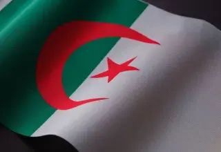 Closeup of the Algerian flag displaying its emblem on textured fabric.