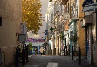 Idyllic street view with people walking in the warm glow of Marseille, capturing urban charm and local life.