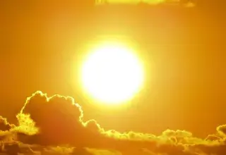 A stunning view of the golden sun shining through clouds at sunset, casting a warm glow.