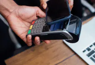 Un client règle un achat en approchant son smartphone d'un terminal de paiement